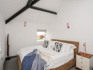 a bedroom with a bed and a window at Cowshed in Pwllheli