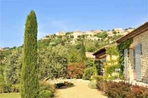 In Gordes, facing the entire Luberon Park a beautiful 5 bedrooms house في جورد: حديقة بها شجرة كبيرة بجوار مبنى