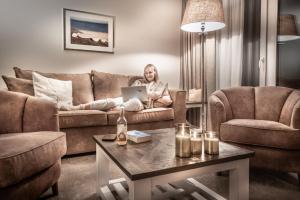 a woman sitting on a couch with a laptop in a living room at Aparthotel Friesenhof in Wenningstedt