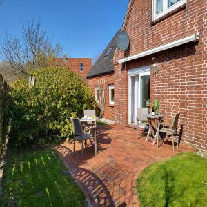 a brick patio with tables and chairs in front of a house at Ferienhaus Op de Diek in Ording