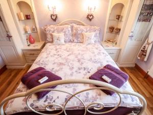 a bedroom with a bed with purple pillows at Tawny Owl Cottage in Louth