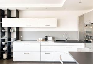 uma cozinha branca com armários brancos e um lavatório em Penthouse vue incroyable lac et montagnes em Annecy