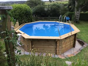 einen Pool in einem Garten mit einem Holzhaus in der Unterkunft Lovely studio apartment near camborne in Camborne