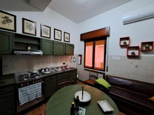 una cocina con armarios verdes y una mesa. en Il Vecchio Piano, en Castrovillari