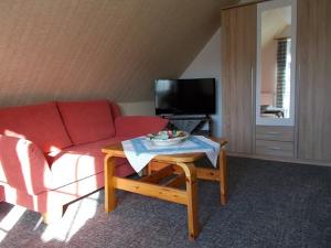 a living room with a red couch and a table at Pension Kraus in Esens