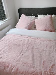 uma cama com um cobertor rosa e almofadas em Shared Modern Apartment Double Bedroom With Attached Bath em Manchester