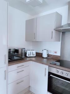 a kitchen with white cabinets and a stove top oven at Shared Modern Apartment Double Bedroom With Attached Bath in Manchester