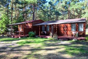 una cabaña de madera en el bosque con un patio de césped en Domek Letniskowy Diana en Pogorzelica