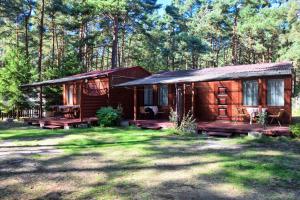 a log cabin in the woods with a grass yard at Domek Letniskowy Paweł in Pogorzelica