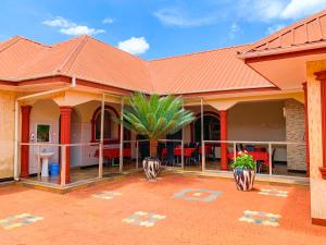 a house with a red roof and a palm tree at Spring Hills Hotel - Morogoro in Morogoro