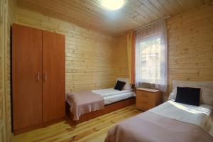 a room with two beds and a cabinet and a window at Domek Letniskowy Diana in Pogorzelica
