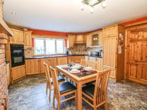 uma cozinha com armários de madeira e uma mesa e cadeiras em Kiltymon Cottage em Ahakista
