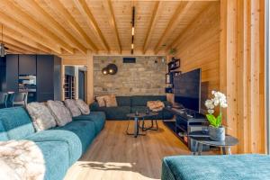 a living room with a blue couch and wooden ceilings at Villa Wood - Gîte de prestige en Ardennes - 10 personnes - Sauna, jacuzzi, piscine et billard in Tenneville