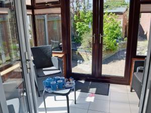 a porch with two chairs and a table with mugs on it at Dormouse Cottage in Sea Palling