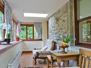 a living room with a table and a stone wall at Old Stones in Glendevon