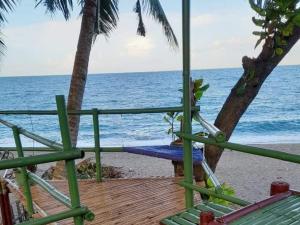 una terraza con sillas y un árbol en la playa en Toni Arts Villa en Nabas