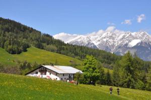 una casa en una colina con montañas en el fondo en Stubai Apartment Telfes, en Telfes im Stubai