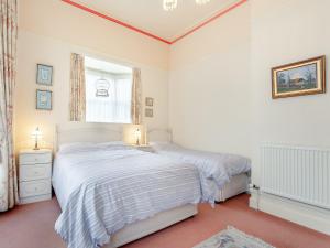 a white bedroom with two beds and a window at Mcsweeney-3536 in Eastbourne
