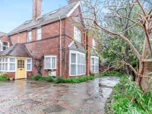 a brick house with a yellow door on a rainy street at Mcsweeney-3536 in Eastbourne
