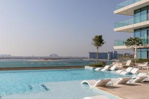 a swimming pool with white chairs and a building at Sea View with Private Beach Access! 3BR & Maid Rm in Dubai