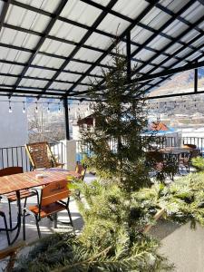 a christmas tree on a patio with a table and chairs at Manoni Ratiani's Guesthouse in Mestia