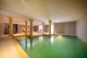 a swimming pool with green water in a building at Hotel Majestic Alsace - Strasbourg Nord in Niederbronn-les-Bains