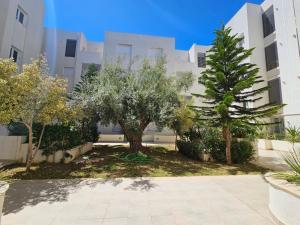 a courtyard with trees in front of a building at Un appartement de charme à Hammamet in Hammamet