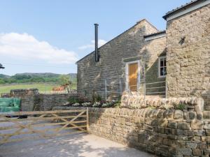 a stone house with a horse in the background at The Barn At Grislow Field in Baslow