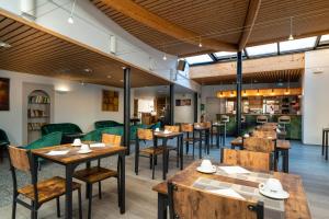 a restaurant with wooden tables and chairs in a room at Hotel Majestic Alsace - Strasbourg Nord in Niederbronn-les-Bains