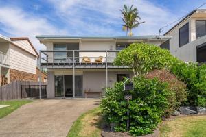 a house with a balcony and a palm tree at Oceanfront Sandy Beach Couples Getaway in Emerald Beach