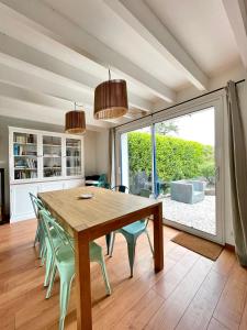 une salle à manger avec une table en bois et des chaises vertes dans l'établissement Maison familiale 11 couchages, proche de La Palue, à Crozon