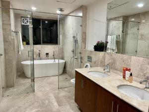 uma casa de banho com 2 lavatórios, uma banheira e um chuveiro em luxury master bedroom with bathtub n private entry best for parties em Nova Deli
