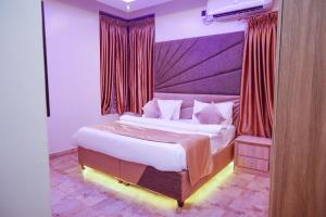 a bedroom with a large bed with red curtains at God's Touch Apartments Signature in Lagos