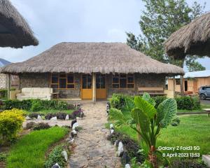 a house with a straw roof with birds in front of it at Le Tai Village Resort near Solio Game Reserve in Mweiga