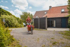 un hombre está montando una bicicleta con una carretilla en Pipowagen De Molenkreek, en Sint-Margriete