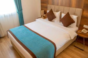 Una cama en una habitación de hotel con un teléfono en una mesa en Dinc Pension, en Bodrum City
