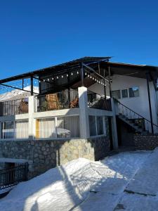 a building with snow on the ground in front of it at Manoni Ratiani's Guesthouse in Mestia