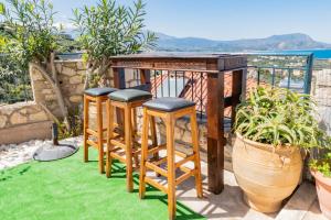 una mesa y taburetes en un balcón con césped verde en Villa Oz IPS Kokkino Chonrio, en Kókkinon Khoríon