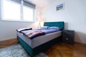Schlafzimmer mit einem Bett mit einem grünen Kopfteil und einem Fenster in der Unterkunft Apartman Zelengora in Tjentište