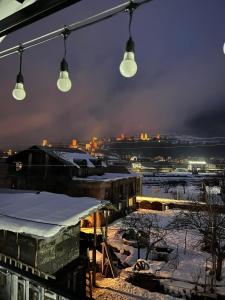 un grupo de luces colgando sobre una ciudad nevada por la noche en Manoni Ratiani's Guesthouse, en Mestia