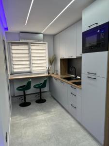 a kitchen with white cabinets and two green chairs at FANTASY ROOM in Iaşi