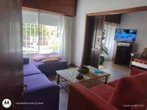 sala de estar con sofás morados y TV en Mi casita en Tandil