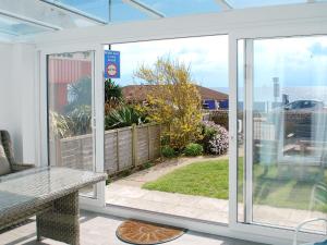 a conservatory with a sliding glass door with a view of a yard at Shoreline in Sandown