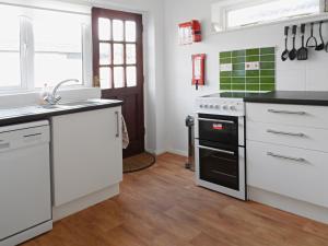 a kitchen with white cabinets and a stove top oven at Shoreline in Sandown