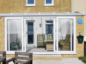 a conservatory with white doors and chairs on a house at Shoreline in Sandown