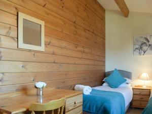 1 dormitorio con pared de madera, mesa y cama en Lodge 3 en Kinlet