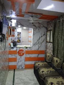 Habitación pequeña con sofá y barra. en Hotel Swarajya Palace en Agra