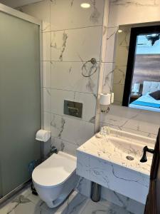 een badkamer met een toilet, een wastafel en een spiegel bij Dinc Pension in Bodrum City