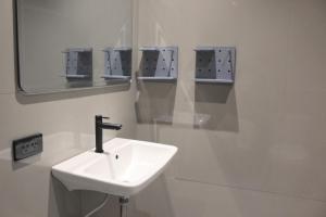 a white bathroom with a sink and a mirror at Nato house Ekkamai in Bangkok