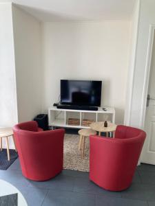 uma sala de estar com duas cadeiras vermelhas e uma televisão em Marie Louise em Montreuil